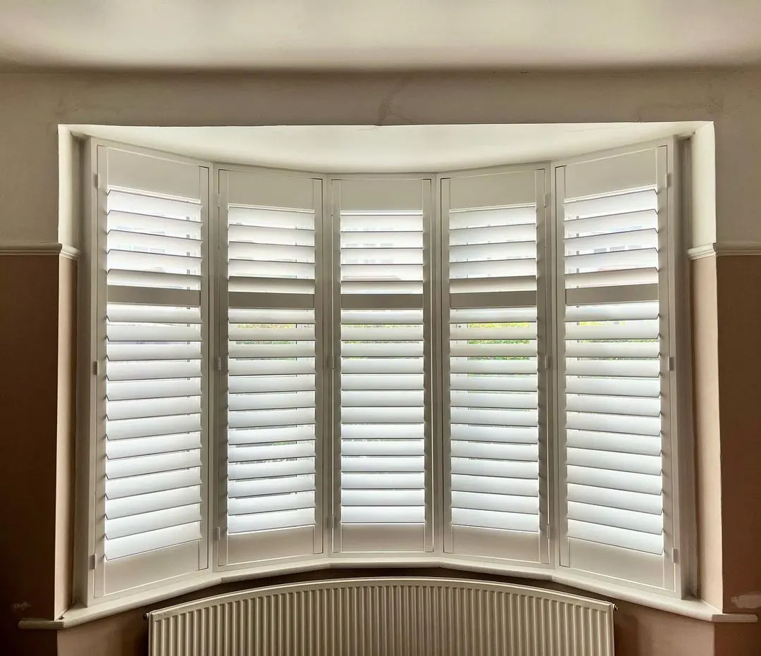 White plantation shutters fitted across a bay window – Erdington Blinds